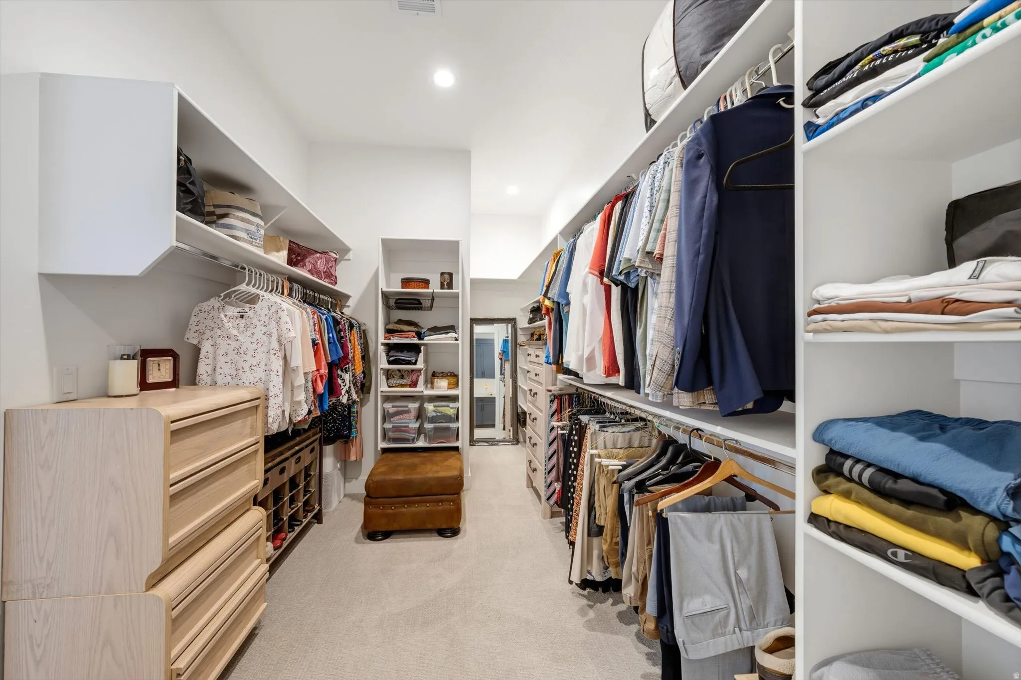 Walk-in closet featuring extensive built-in shelving, hanging rods, recessed lighting, and soft carpet flooring