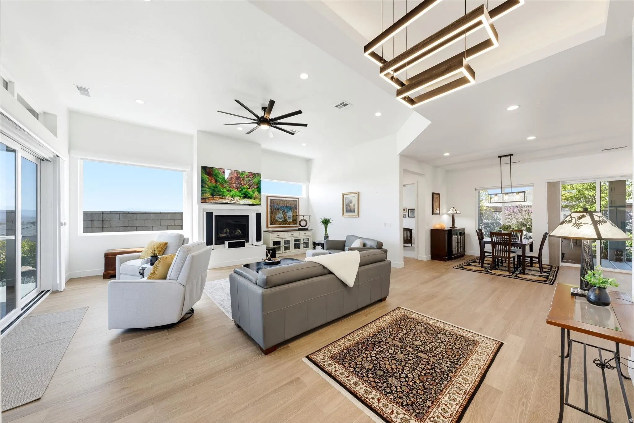 Vaulted ceilings with recessed lighting, wood-finish flooring, a contemporary fireplace, and sliding glass doors