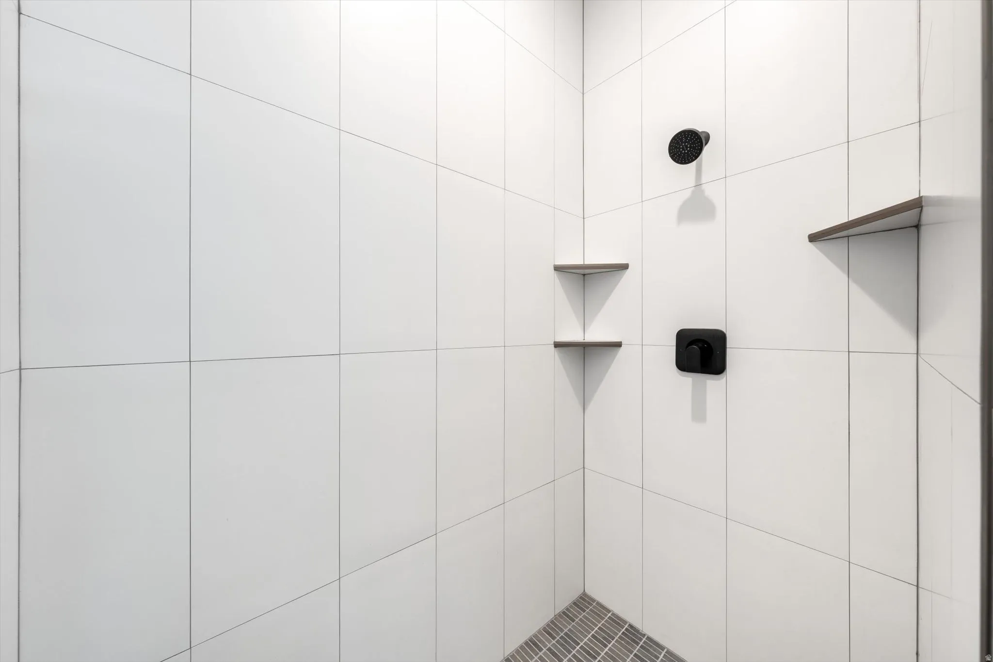 White subway tile shower enclosure with matte black fixtures and built-in corner shelving