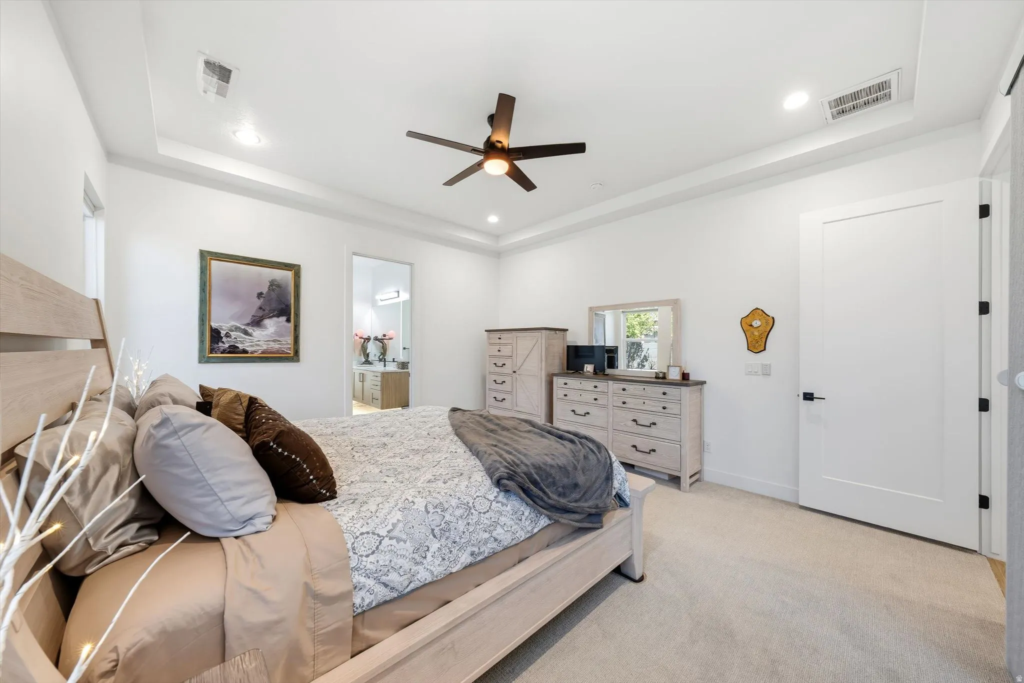 Tray ceiling with recessed lighting, ceiling fan with integrated lighting, flat panel interior door, and light-toned carpeting