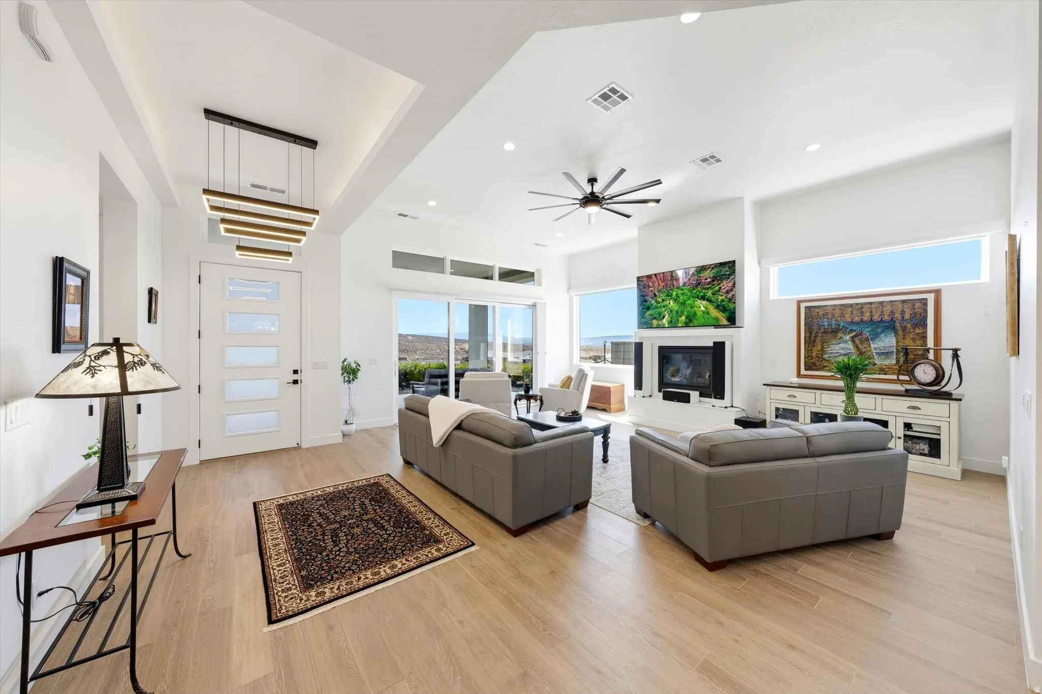 Vaulted ceilings, wood-finish flooring, a contemporary fireplace, and an expansive sliding glass door