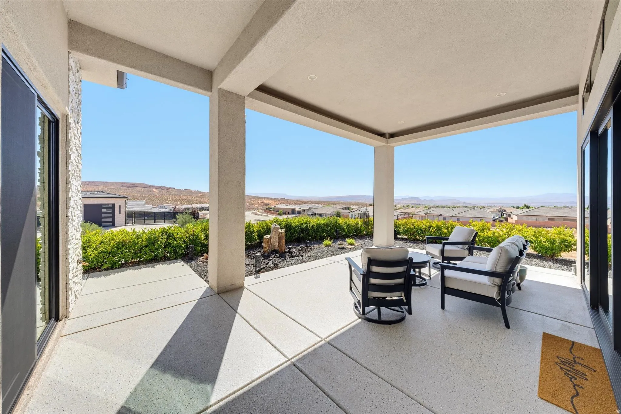 Expansive covered patio featuring a concrete surface, recessed lighting, and lush landscaping