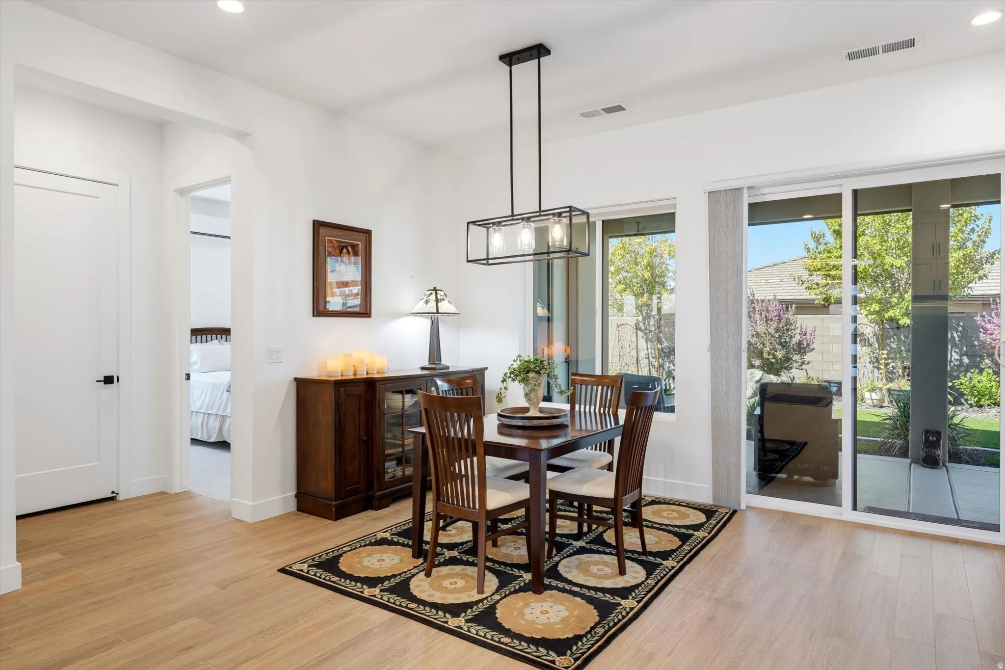 Recessed lighting, wood-finish flooring, white walls, built-in ceiling vents, and a contemporary linear chandelier