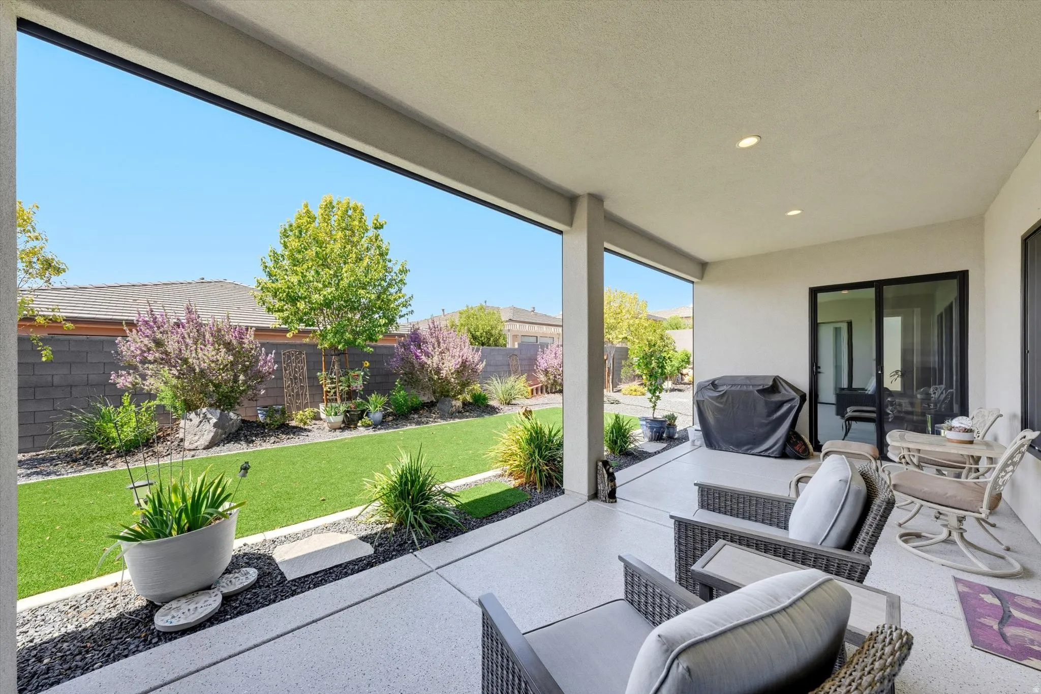 Expansive covered patio with recessed lighting, concrete flooring, and direct access to the backyard