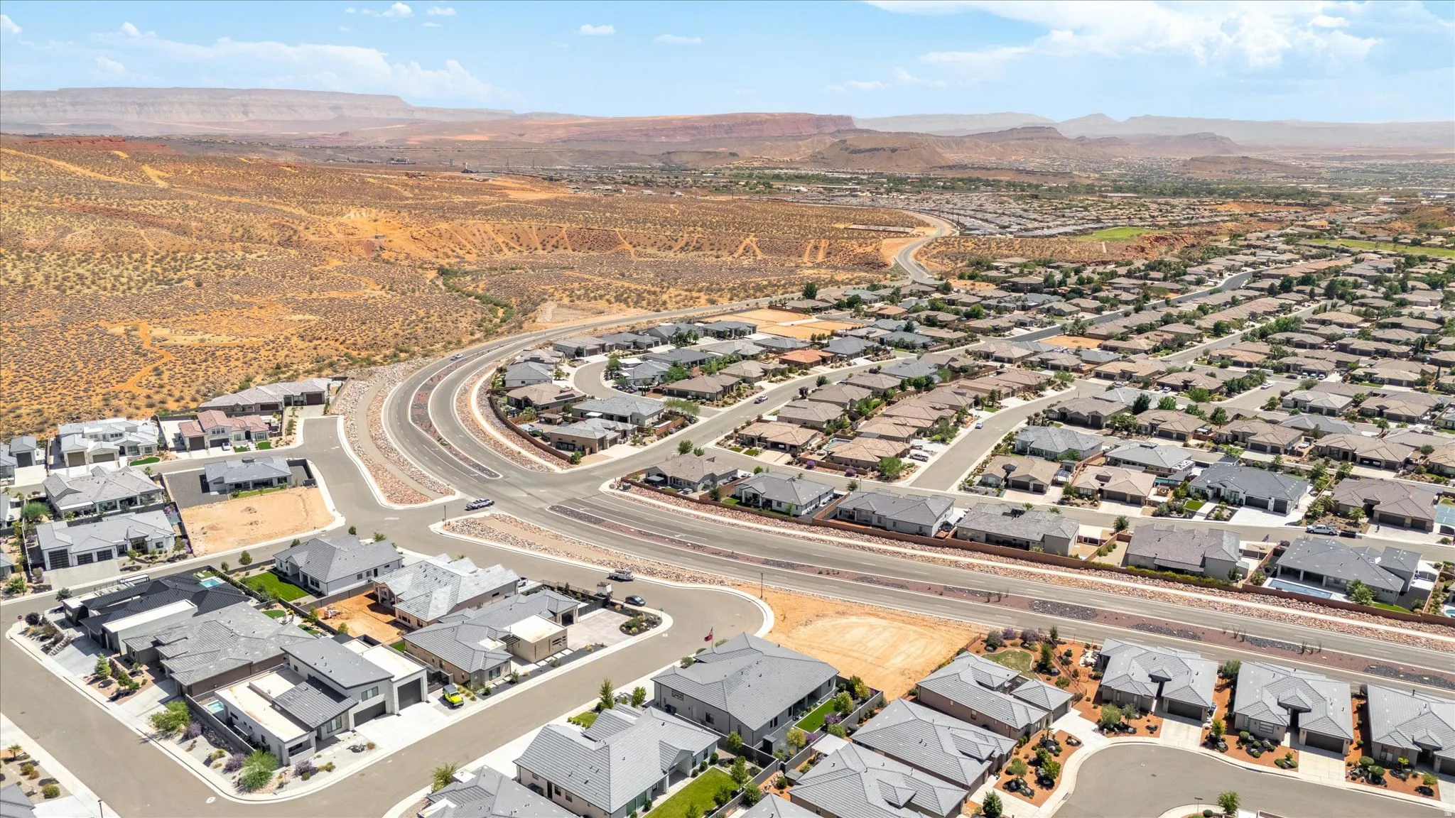 Expansive residential community with diverse modern single-story homes, surrounded by natural desert landscapes and distant mountains