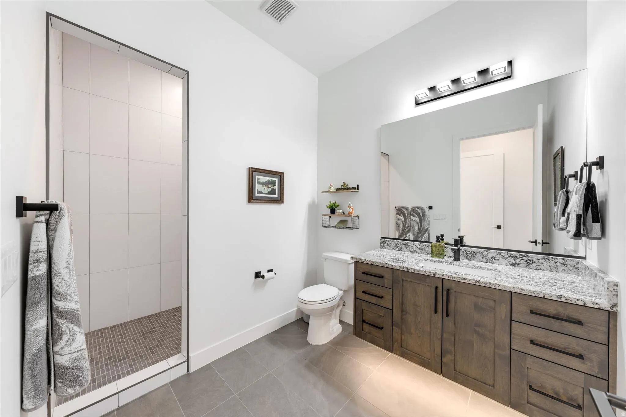 Sleek bathroom featuring a frameless glass-enclosed shower with tiled walls and a mosaic floor