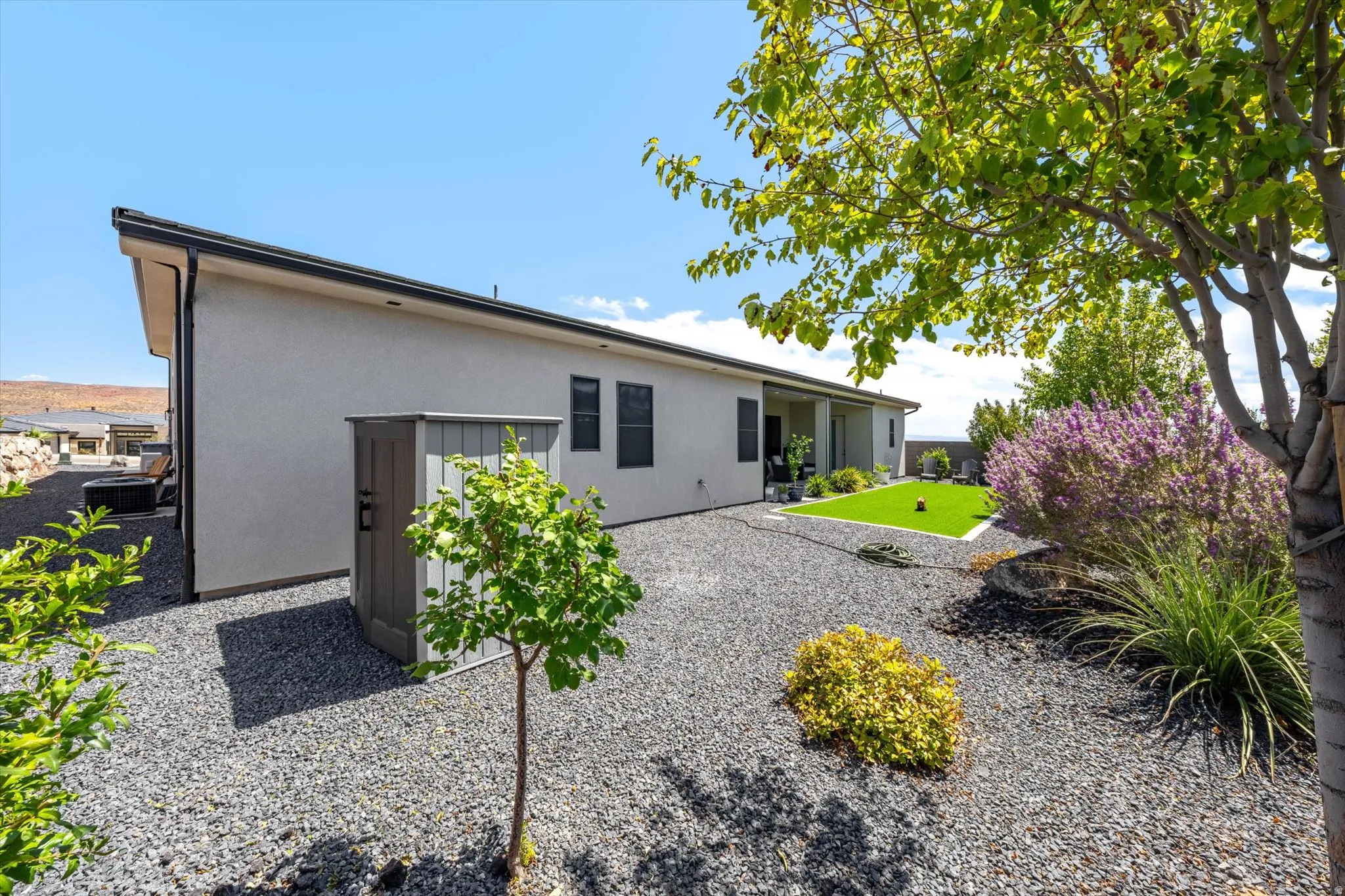 Spacious exterior with gravel landscaping, a shed, and a covered patio