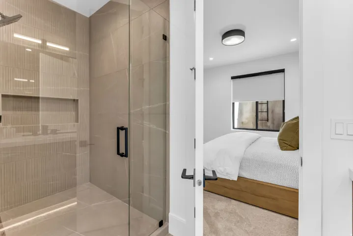 Walk-in shower with full-height tile surround, glass enclosure, and matte black fixtures