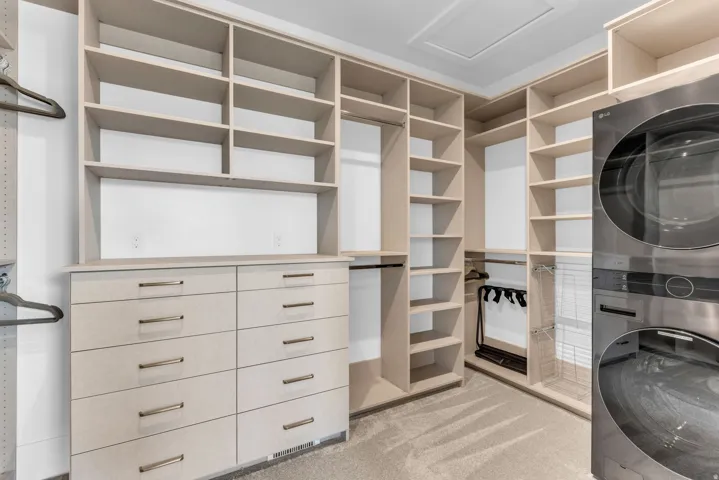 Custom closet system with integrated shelving, multiple hanging rods, built-in drawers with modern hardware, and carpet flooring