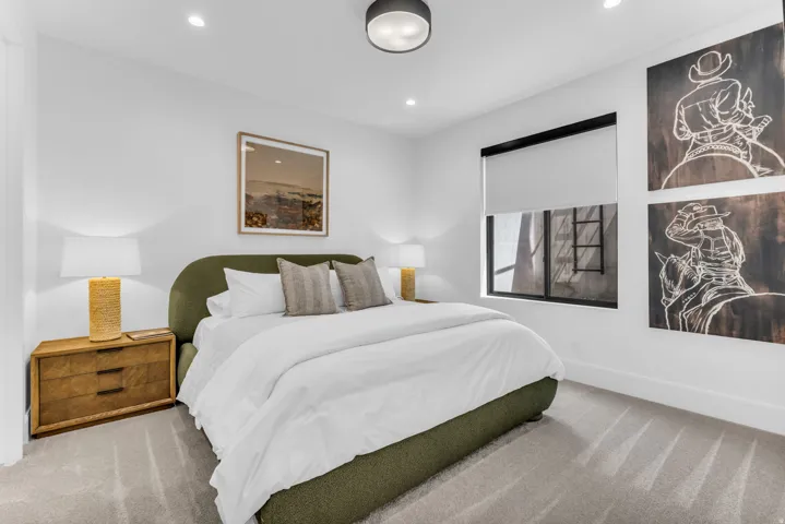 Recessed lighting, a flush mount ceiling fixture, and a window with a roller shade illuminate the space