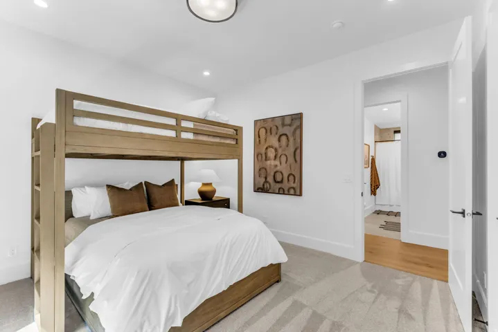Recessed lighting, wood-finish bunk beds, carpeted flooring, white walls, and a flat-panel door