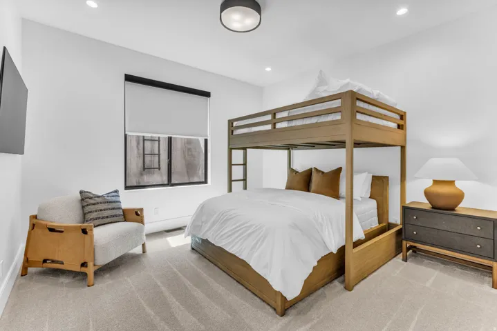Recessed lighting, light-toned carpeting, and a window with a roller shade