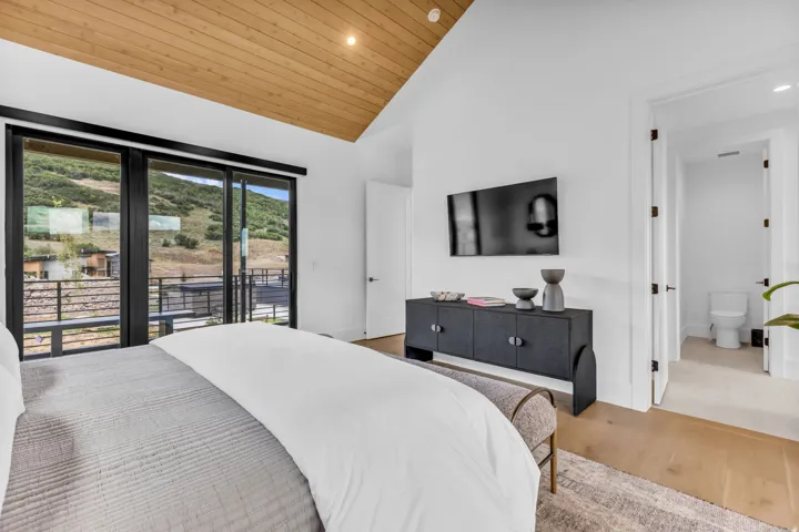 Vaulted wood-paneled ceiling, wood-finish flooring, sliding glass doors with dark frames, white walls, and a recessed light fixture