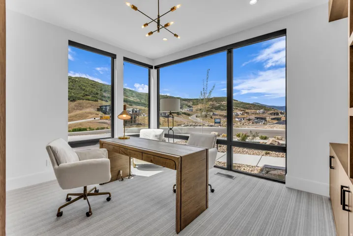 Expansive corner windows with dark framing, a contemporary chandelier, recessed lighting, and built-in wood-finish cabinetry