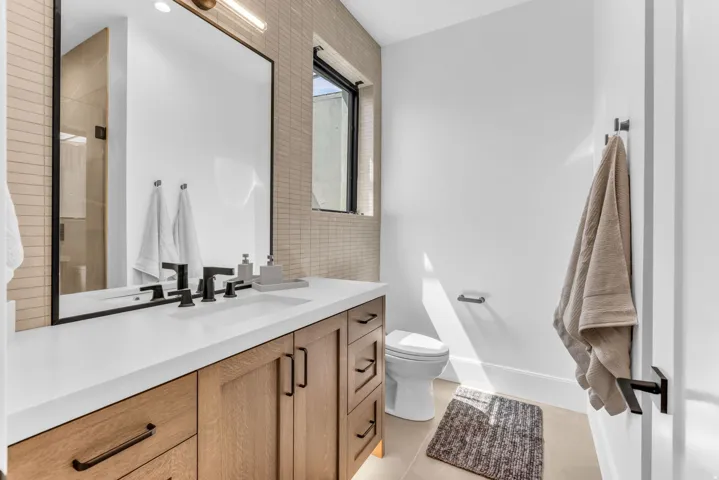 Wood-finish vanity with white countertop, integrated sink, and matte black fixtures