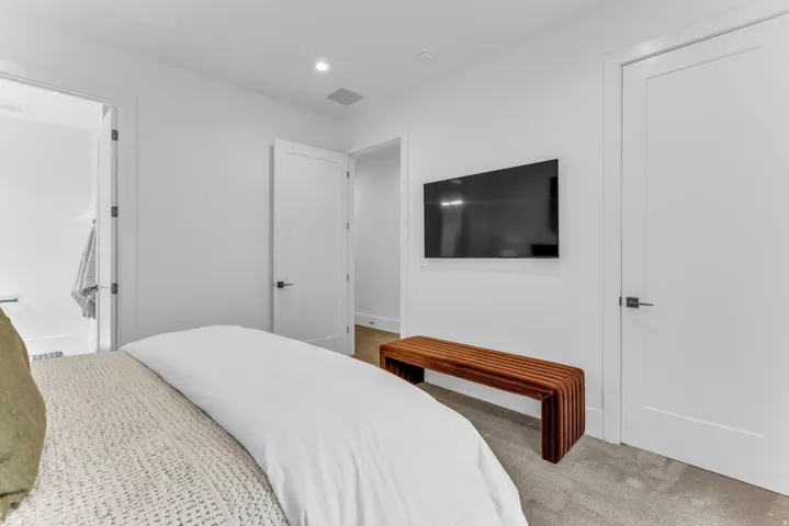 Recessed lighting, wood-finish flooring, white flat-panel doors with dark hardware, and grey carpet
