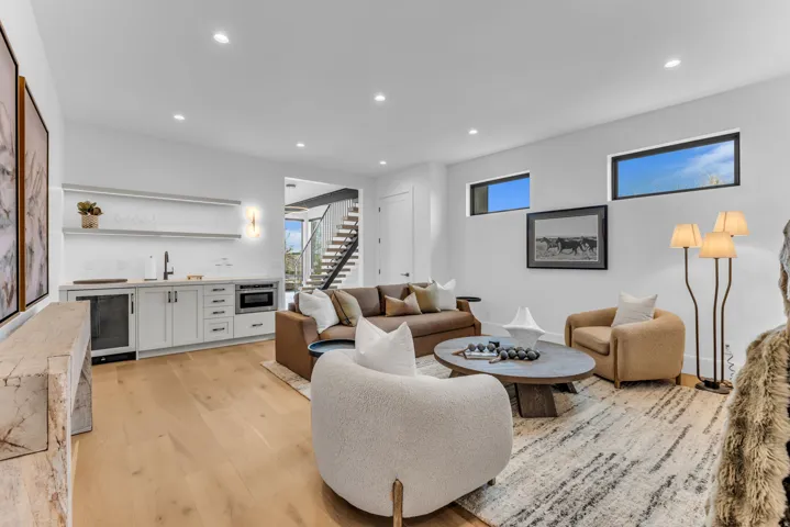 Light wood-finish flooring, built-in wet bar with under-counter refrigeration, recessed lighting, and horizontal windows