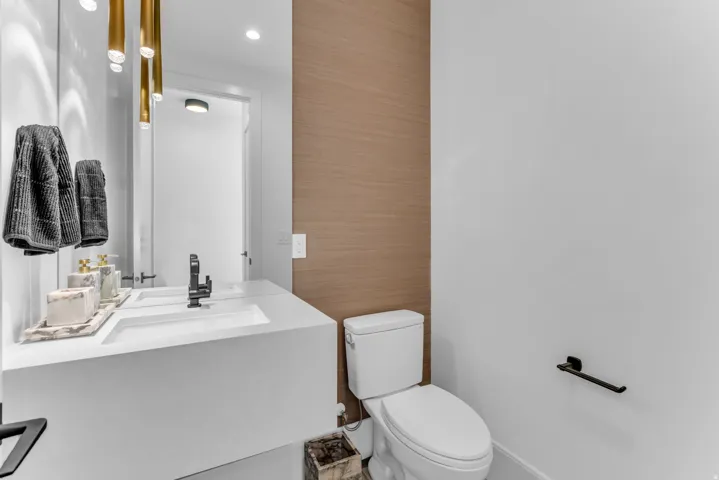 Integrated vanity with a rectangular sink, wall-mounted faucet, and gold-toned pendant lighting