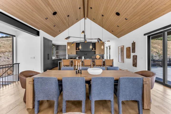 Vaulted wood-paneled ceiling, integrated recessed lighting, wood-finish flooring, sliding glass door, and modern chandelier