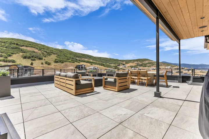 Expansive rooftop deck featuring a tiled surface, protective railing, and a wood-paneled ceiling overhang