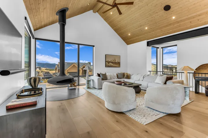 Vaulted wood-paneled ceiling with recessed lighting, floor-to-ceiling windows, wood-finish flooring, and a suspended fireplace