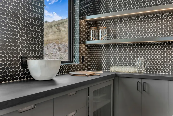 Black penny tile backsplash with open shelving and integrated lighting