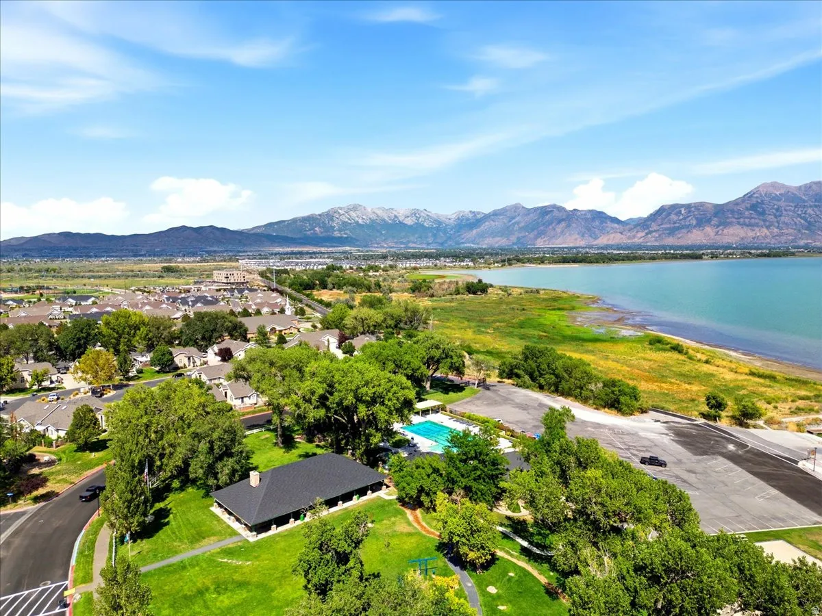 Expansive residential area featuring a distinct community building, a large swimming pool, and a paved parking area