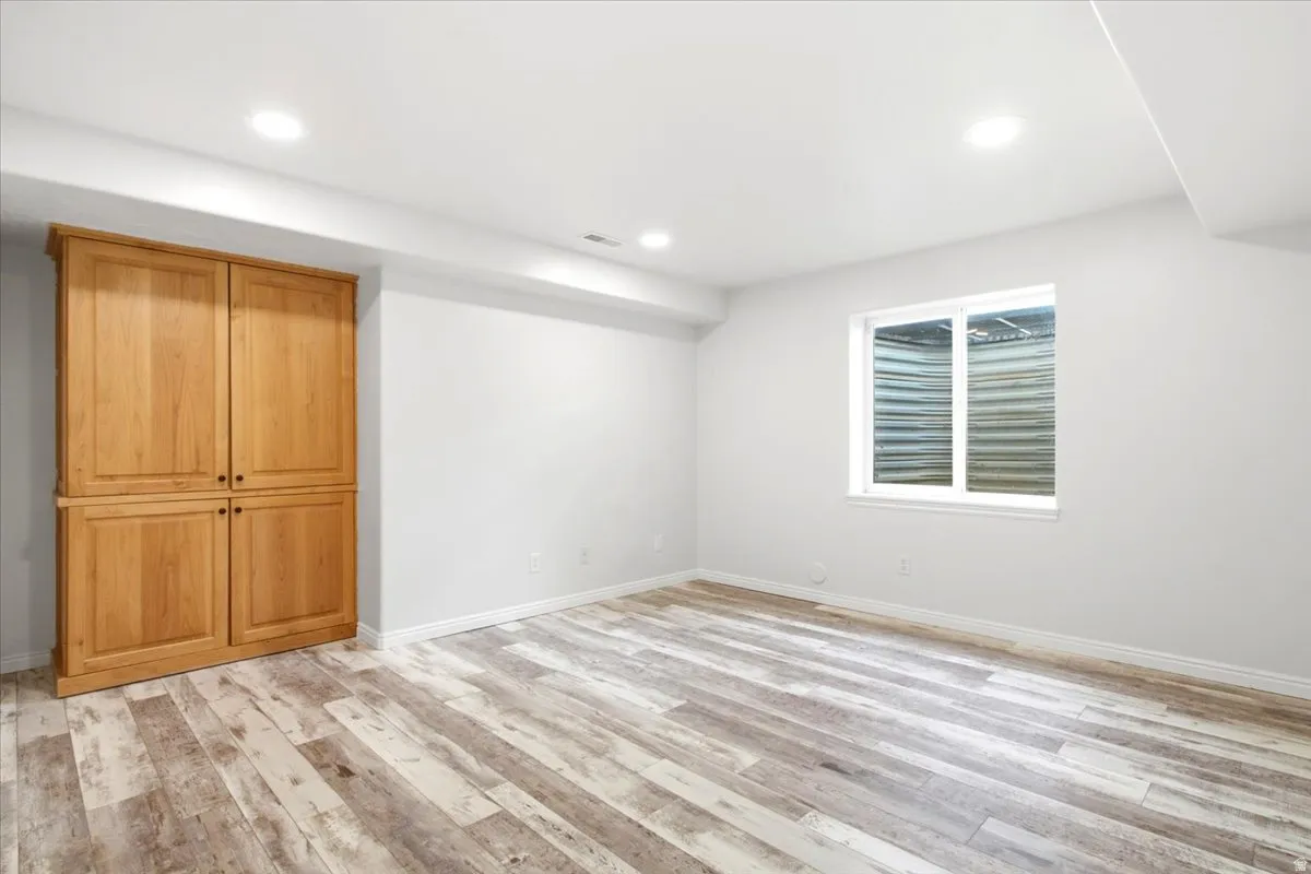 Bedroom 6. Light wood-finish flooring, recessed lighting, white walls, and a built-in wooden cabinet