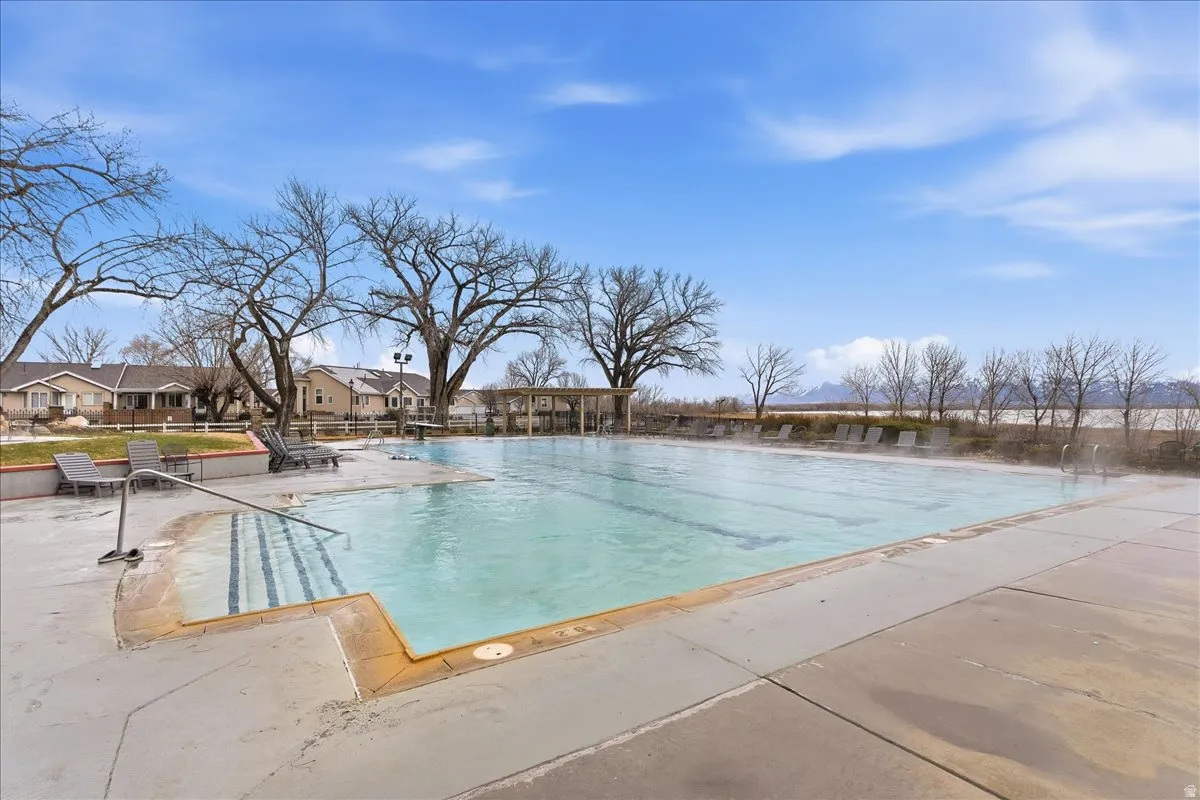 Expansive outdoor pool with integrated steps and handrails, surrounded by concrete decking