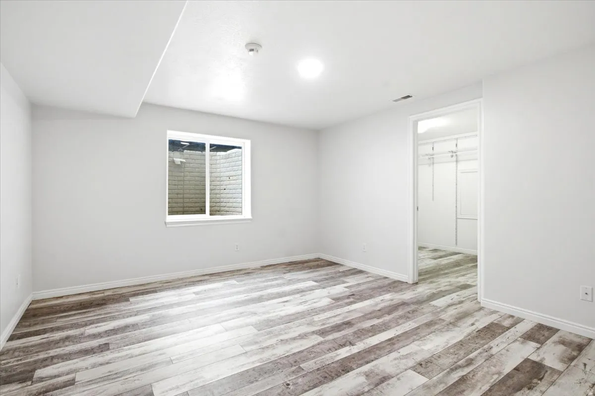 Bedroom 4. Wood-finish flooring, recessed lighting, egress window, and a dedicated closet space with built-in shelving
