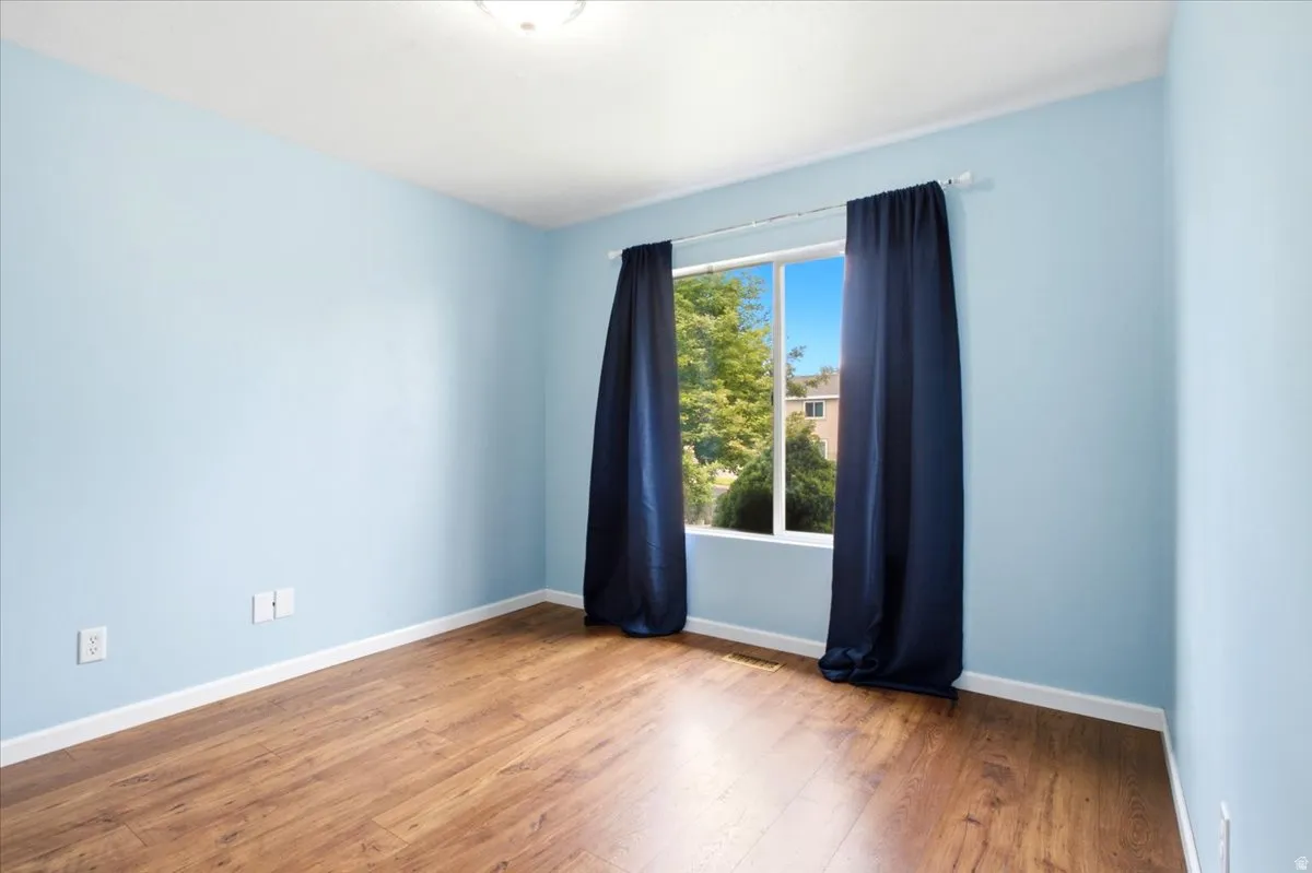 Wood-finish flooring, white trim, and a window with a white frame