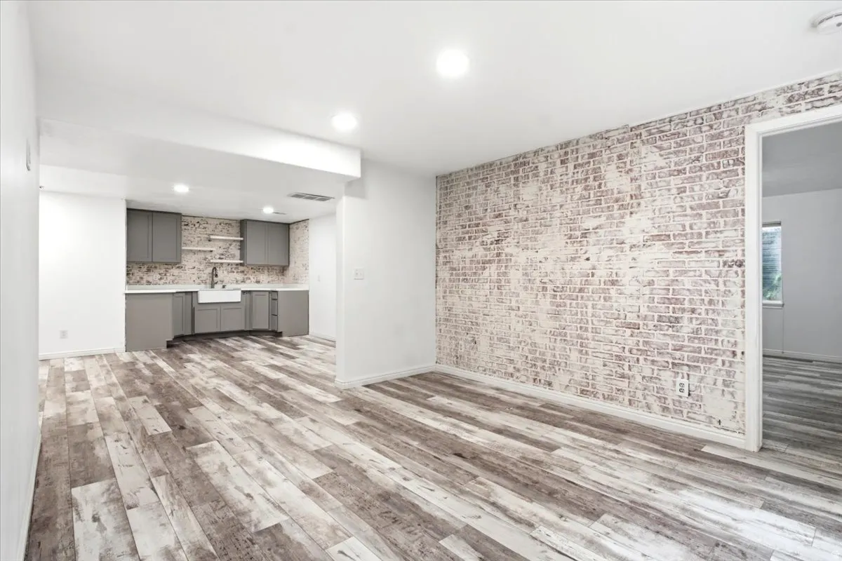Wood-finish flooring throughout, featuring a white-washed brick accent wall