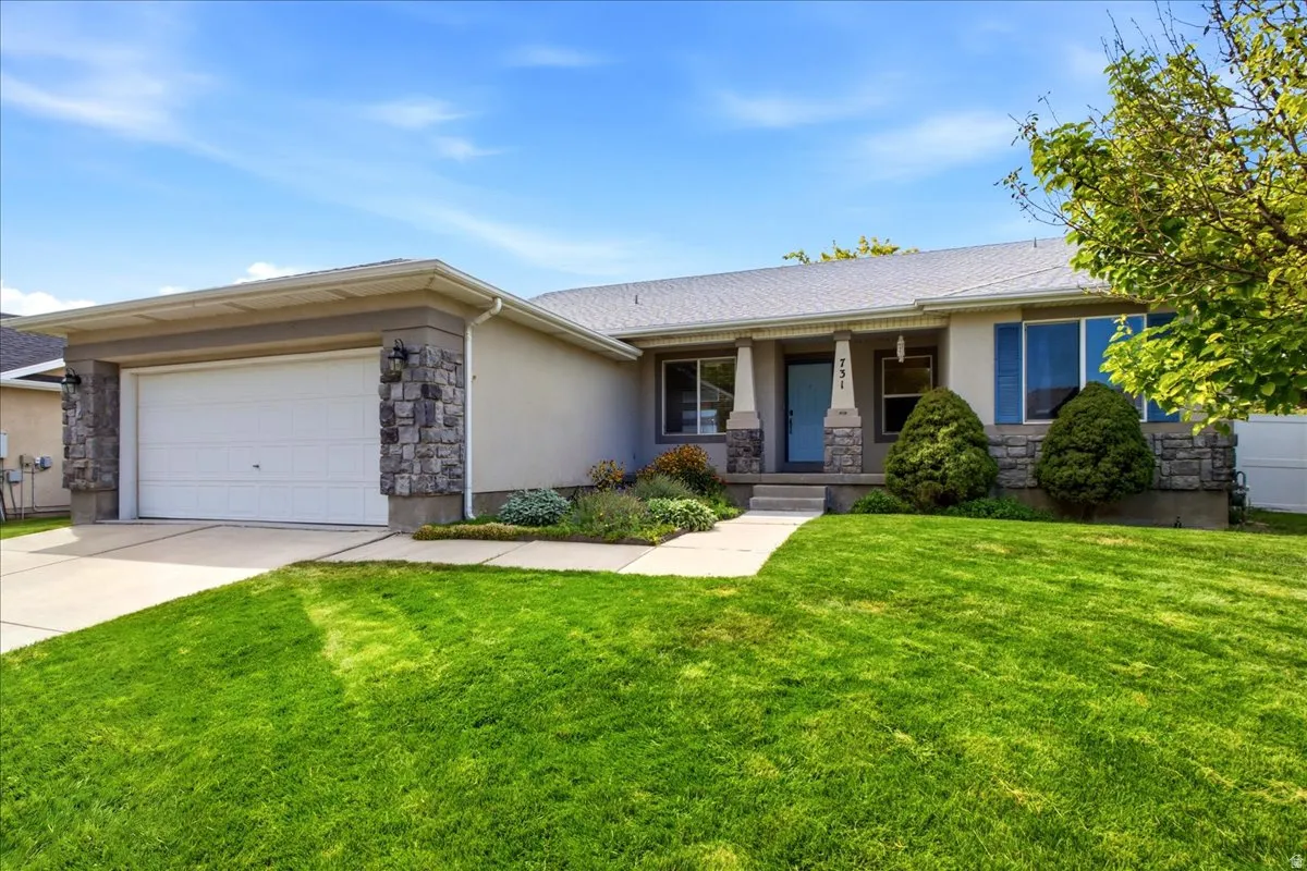 Stucco and stone exterior with an attached garage, covered entry, and a concrete walkway