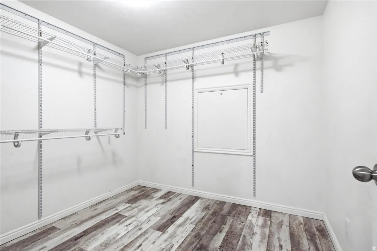 Huge Walk-in closet featuring wood-finish flooring, white walls, and a multi-level wire shelving system