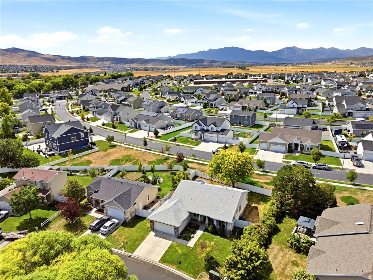 Residential neighborhood with varied architectural styles, paved streets, and mature landscaping, set against a mountain backdrop