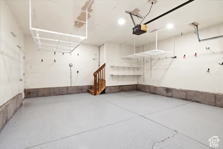 Expansive Garage Space Featuring a Light Gray Epoxy Floor, and Plenty of Overhead Storage, and Garage Side Door