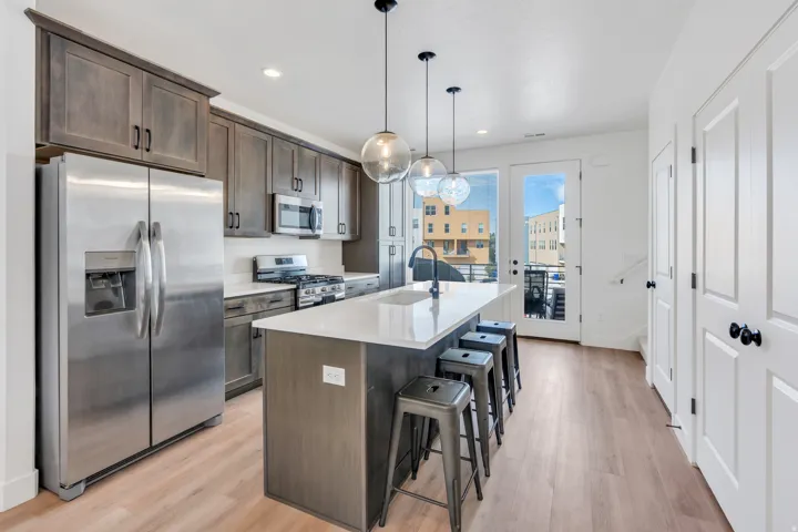 Open kitchen with oversized island, quartz countertops and stainless steel appliances.