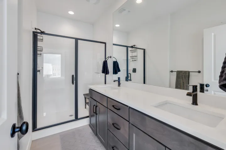 Primary bathroom with dual vanities and large walk-in shower.