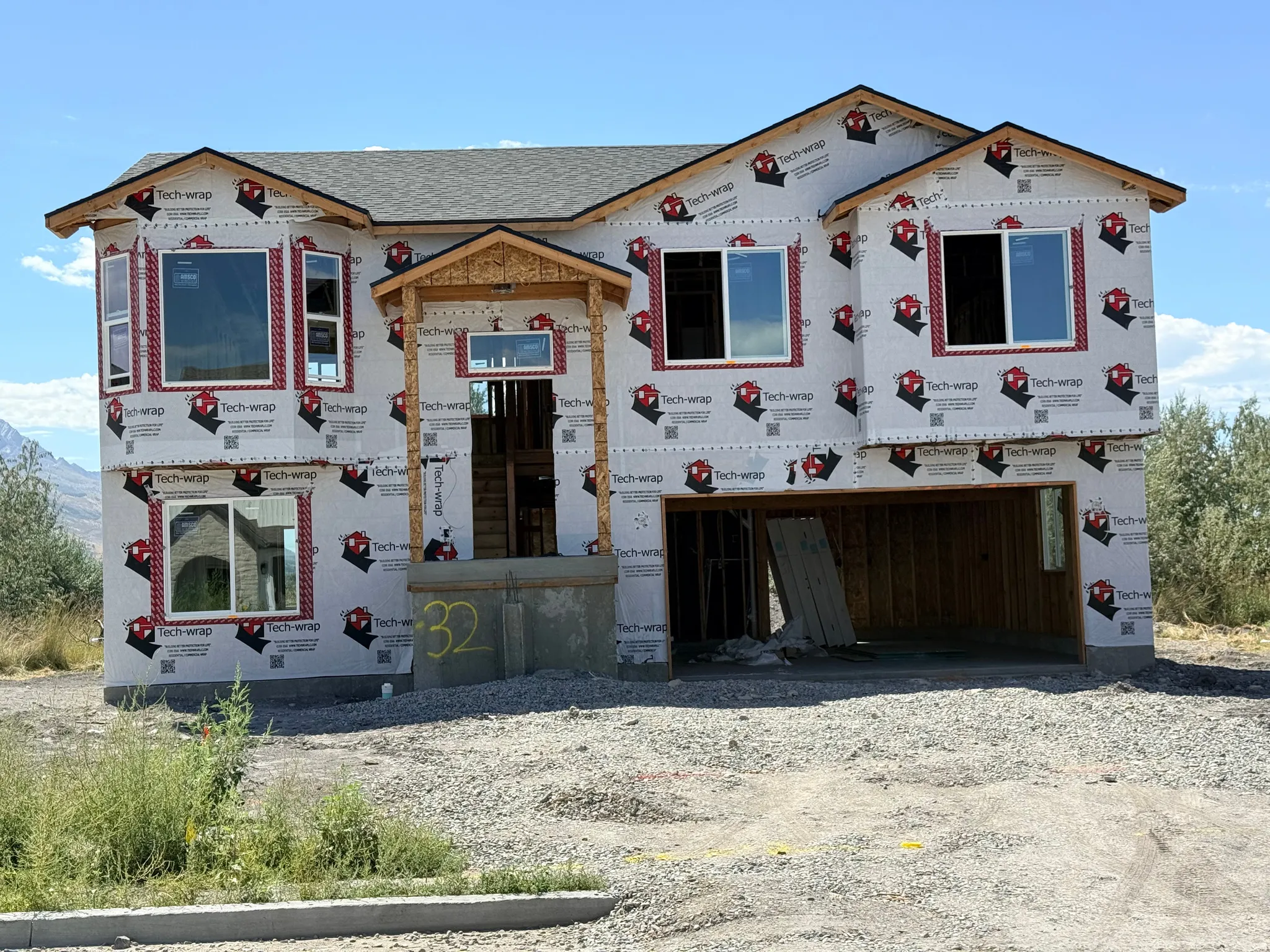 New construction framing with a two-story bay window, a covered entry, and an integrated two-car garage