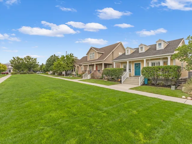 Expansive green space with sidewalks, mature trees, and residential properties featuring dormer windows
