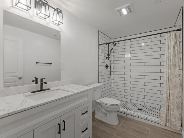 White vanity with a single basin sink and a stone-finish countertop