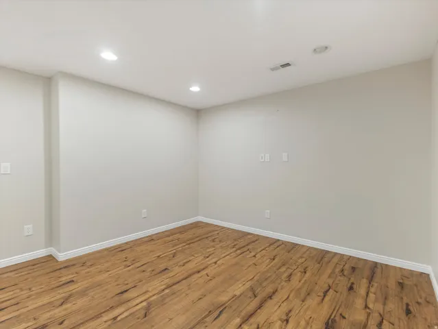 Extra room, it could be a studio or movie room.  Recessed lighting illuminates the wood-finish flooring and light-toned walls