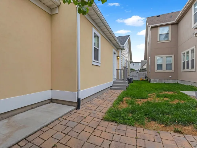 Paved patio area, adjacent concrete pad, exterior lighting fixture, and a two-step deck with railings