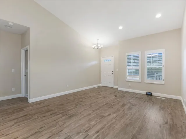 Vaulted ceiling, wood-finish flooring, recessed lighting, chandelier, and white plantation shutters