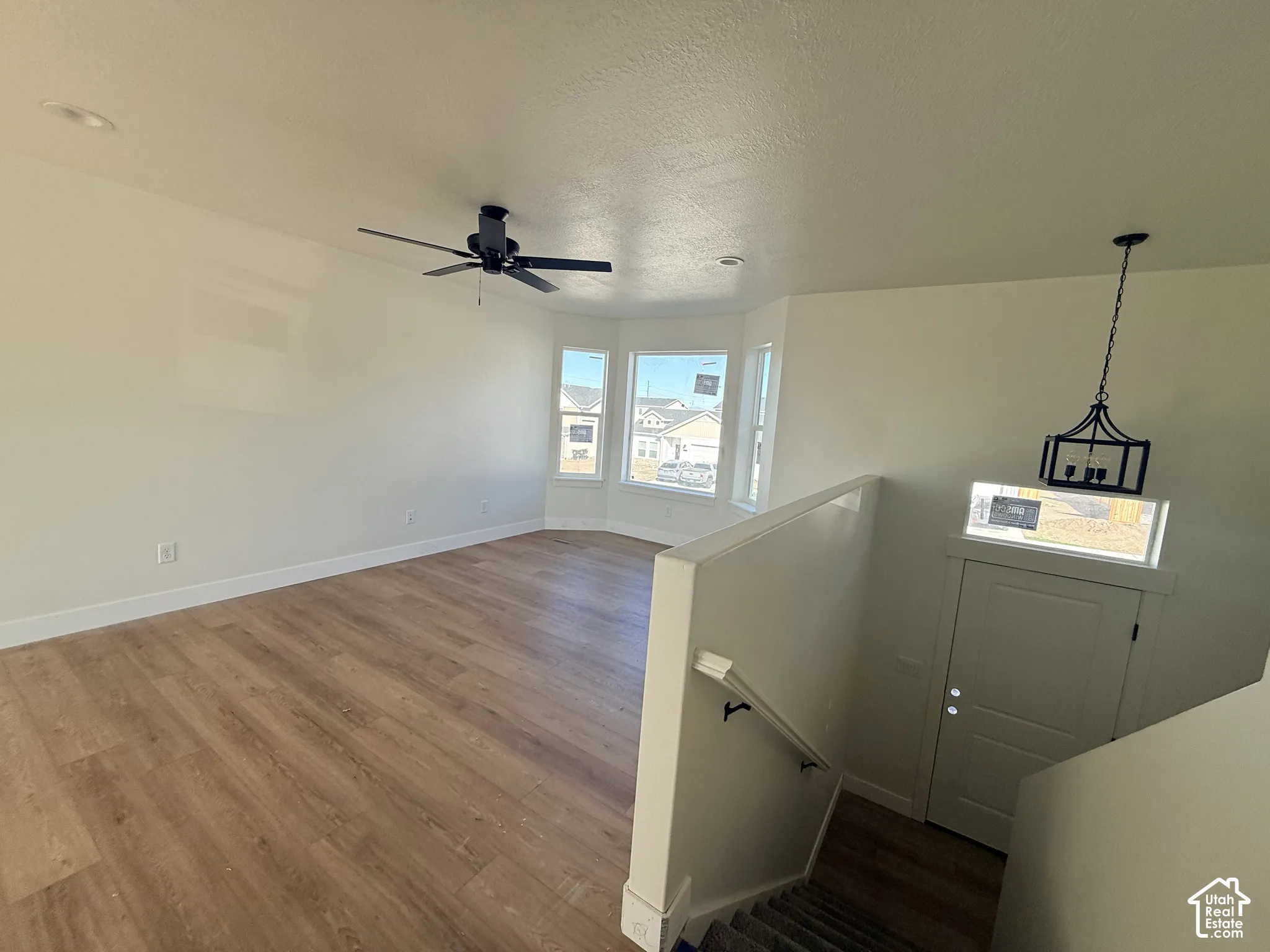 Open living area featuring wood-finish flooring, recessed lighting, a ceiling fan, a bay window configuration, and a hanging pendant light fixture