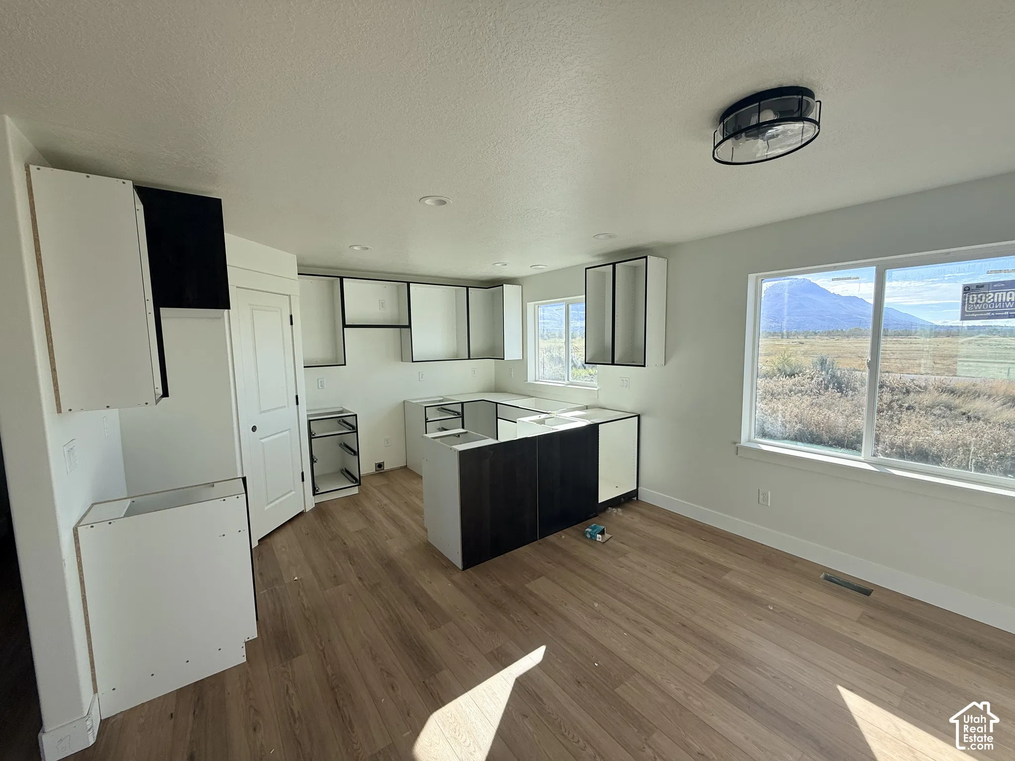 Kitchen area featuring two-tone cabinetry, wood-finish flooring, recessed lighting, a flush-mount ceiling fixture, and large windows with mountain scenery