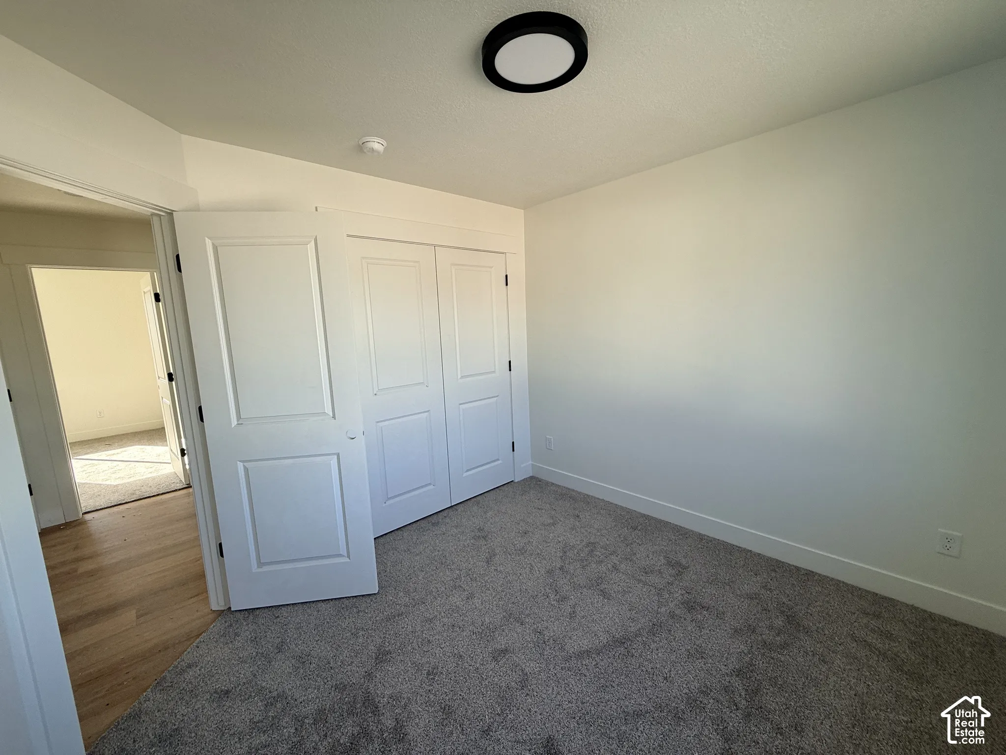 Neutral-toned carpeting, white two-panel interior doors, recessed closet storage, and a modern circular flush-mount ceiling light fixture