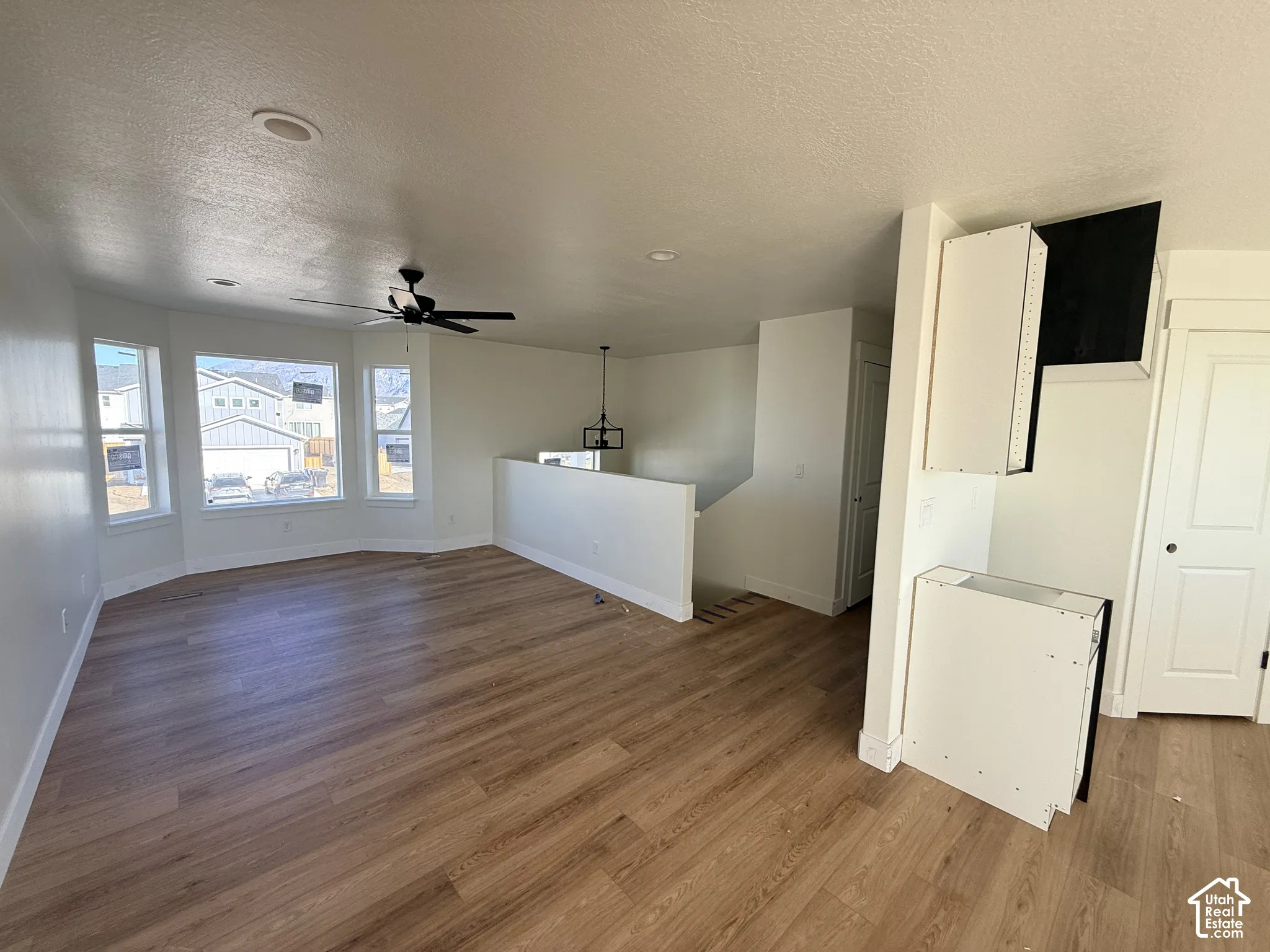 Open-concept interior featuring wood-finish flooring, a bay window, recessed lighting, a ceiling fan, and built-in cabinetry