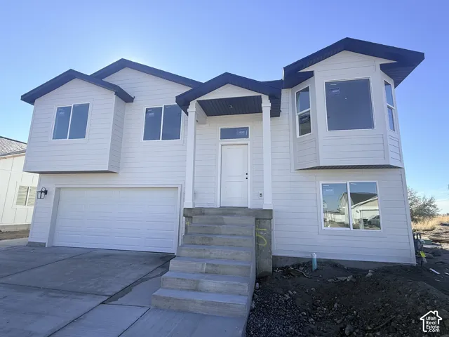 Two-story exterior featuring horizontal siding, a gabled roofline with dark trim, a covered front entry with columns, and an attached two-car garage