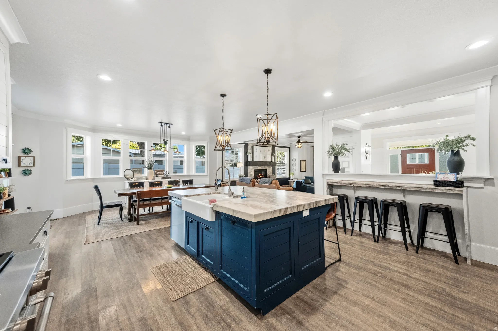 Spacious kitchen featuring a large island with a farmhouse sink, wood-finish flooring, recessed lighting, and a breakfast bar